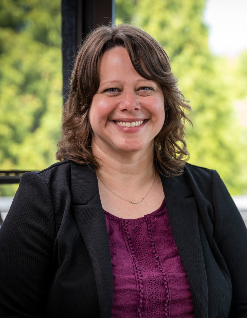 Headshot of our Executive Director, Jennifer Knapp. She is a white woman, with brown shoulder-length hair. She is wearing a dark purple top with a black blazer.